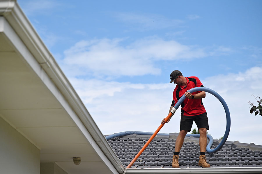 A professional home improvement expert cleaning and maintaining the gutters of a residential home in Springfield, IL.